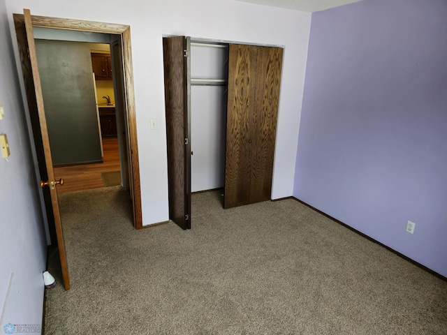 unfurnished bedroom with carpet, a closet, and baseboards