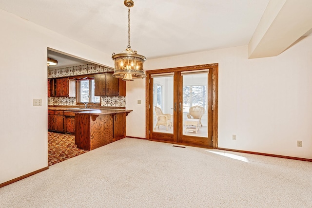 kitchen featuring pendant lighting, kitchen peninsula, dark carpet, and french doors