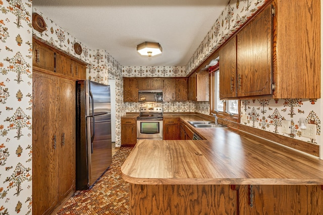 kitchen featuring stainless steel appliances, kitchen peninsula, sink, and a textured ceiling