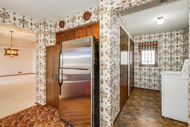 kitchen featuring stainless steel refrigerator, washer / clothes dryer, decorative light fixtures, and a textured ceiling