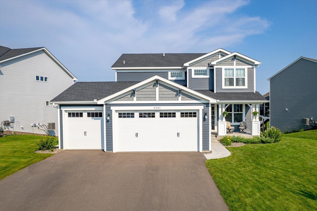 craftsman inspired home with central AC unit, a garage, and a front yard