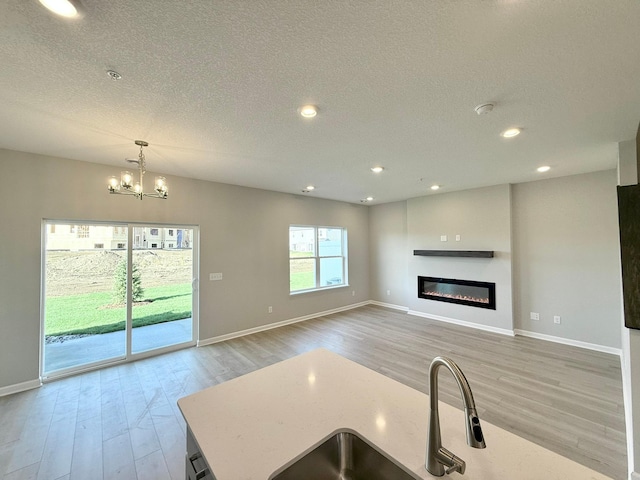 kitchen featuring a textured ceiling, sink, pendant lighting, an inviting chandelier, and hardwood / wood-style floors