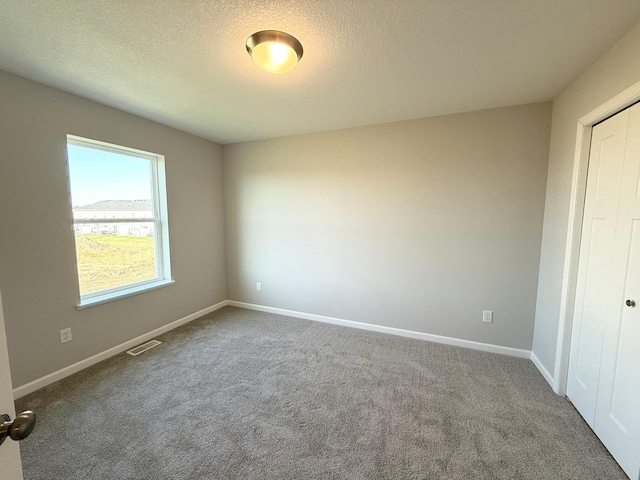 unfurnished room with carpet flooring and a textured ceiling