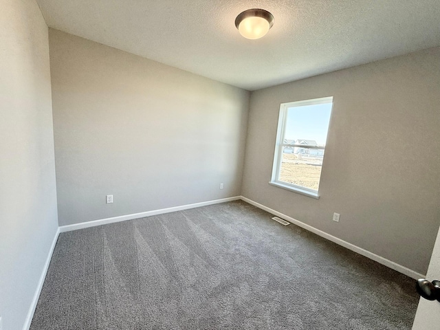 unfurnished room with dark carpet and a textured ceiling