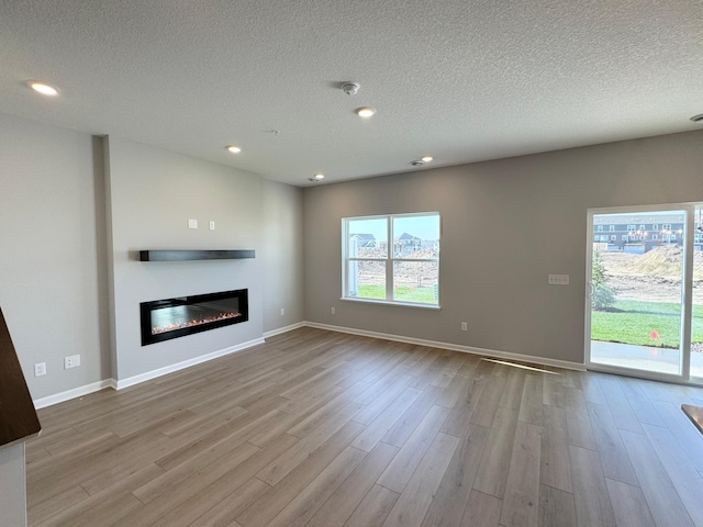 unfurnished living room featuring a textured ceiling and light hardwood / wood-style flooring