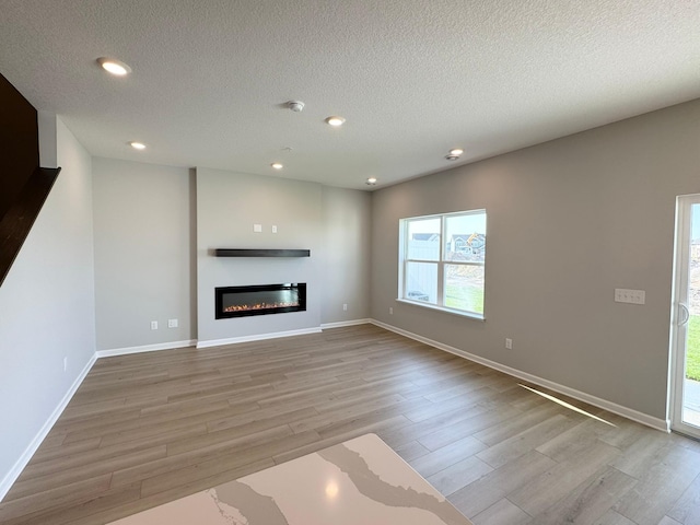 unfurnished living room featuring a textured ceiling and light wood-type flooring