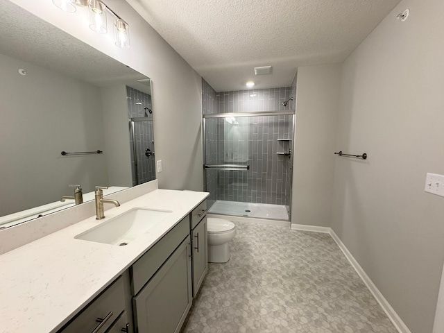 bathroom with vanity, a shower with shower door, a textured ceiling, and toilet