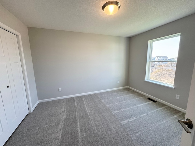 unfurnished bedroom with carpet, a textured ceiling, and a closet