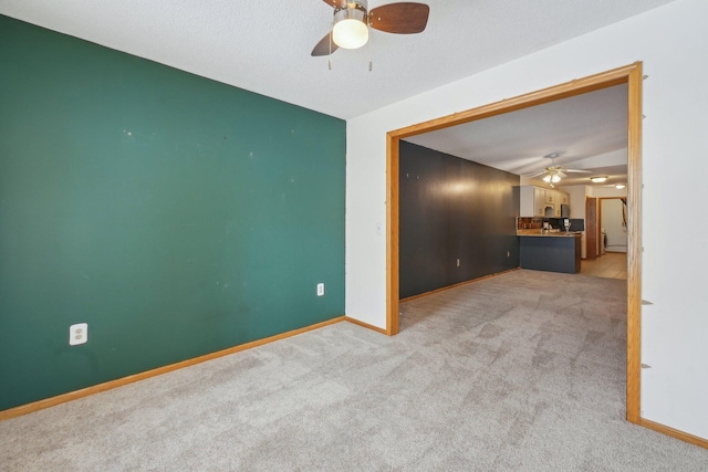 carpeted spare room with ceiling fan and a textured ceiling