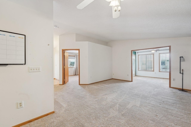 carpeted spare room with ceiling fan, lofted ceiling, and plenty of natural light