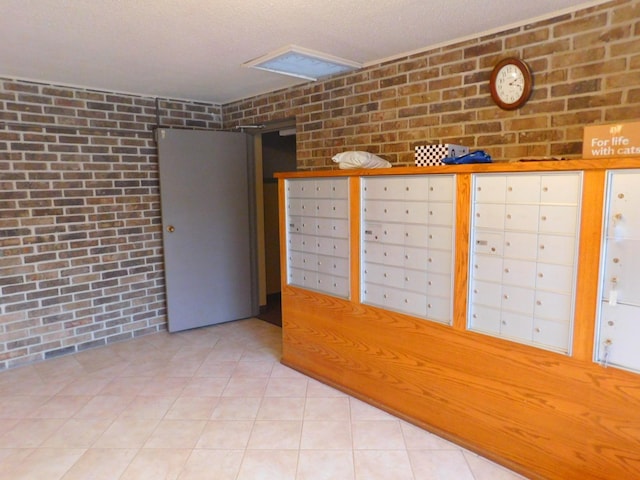 unfurnished room featuring a textured ceiling, a mail area, and brick wall