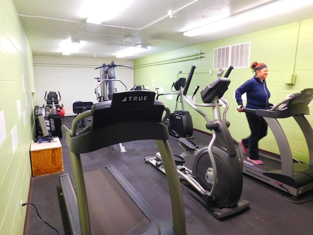 workout area with ceiling fan and a textured ceiling