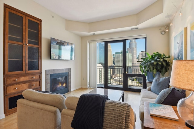 living room with light wood-type flooring and a tiled fireplace