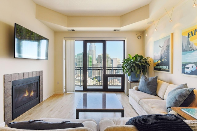 living room with a tile fireplace and light hardwood / wood-style floors