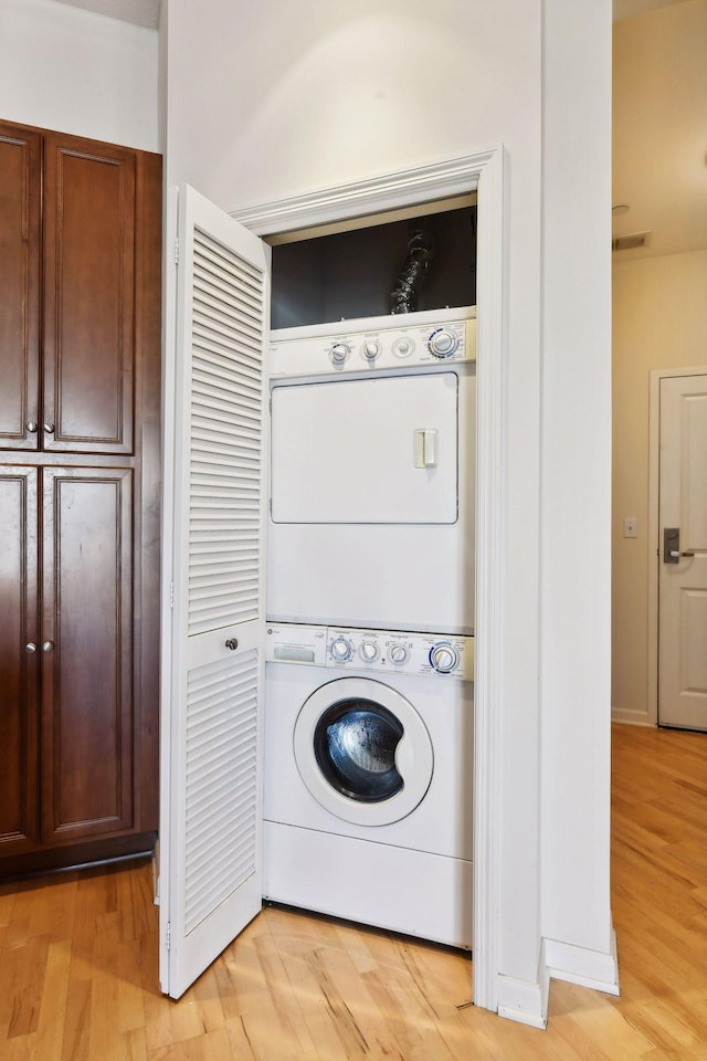 laundry area with light hardwood / wood-style flooring and stacked washer and clothes dryer