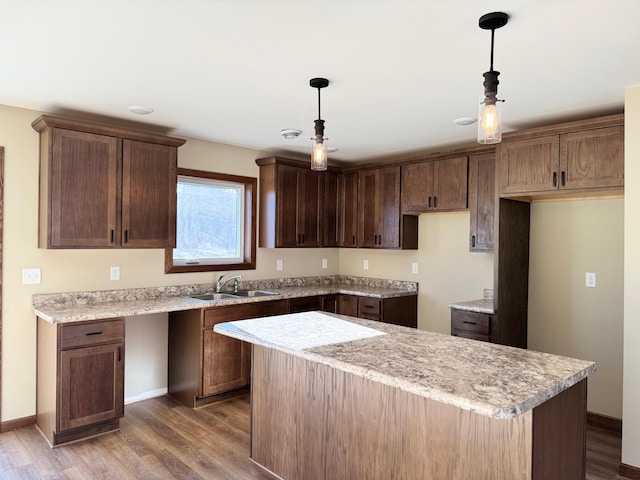 kitchen featuring sink, wood-type flooring, hanging light fixtures, and a kitchen island