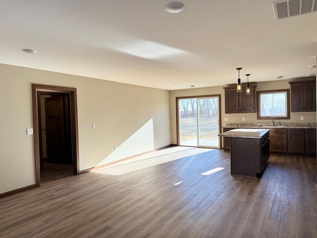 kitchen featuring sink, a kitchen island, dark hardwood / wood-style flooring, and hanging light fixtures