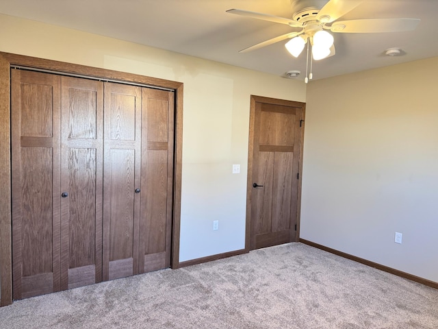 unfurnished bedroom featuring ceiling fan, a closet, and light carpet