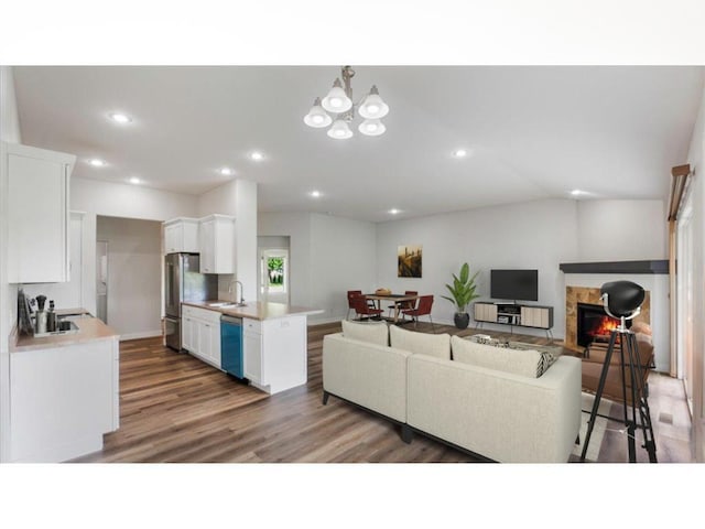 living room with a tile fireplace, lofted ceiling, sink, a chandelier, and dark hardwood / wood-style flooring