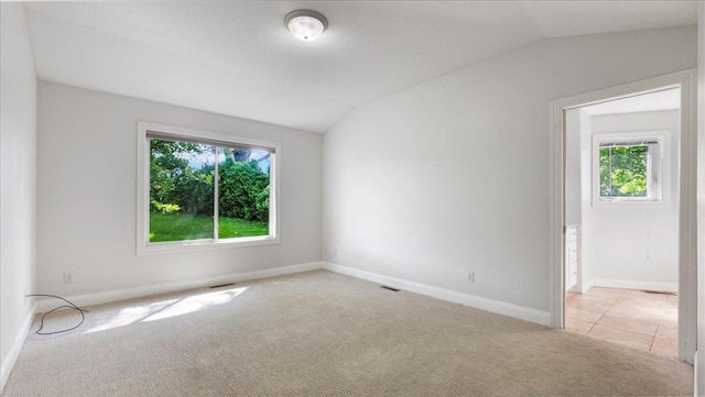 carpeted spare room featuring vaulted ceiling