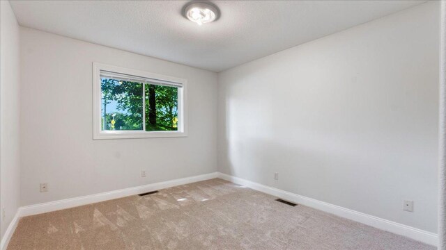 carpeted spare room with a textured ceiling