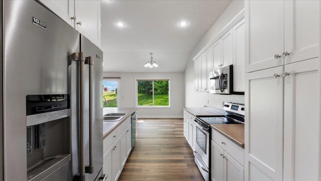 kitchen featuring dark wood-type flooring, sink, white cabinetry, pendant lighting, and stainless steel appliances