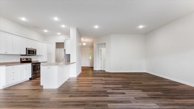 kitchen featuring sink, dark hardwood / wood-style flooring, kitchen peninsula, stainless steel appliances, and white cabinets