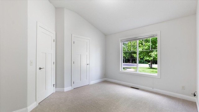 unfurnished bedroom featuring lofted ceiling and light colored carpet