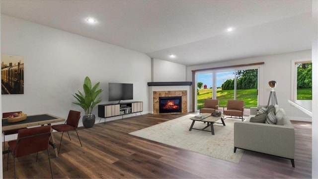 living room with dark hardwood / wood-style flooring, a tiled fireplace, and vaulted ceiling