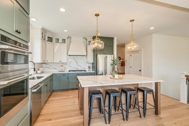 kitchen featuring appliances with stainless steel finishes, light wood-type flooring, a sink, and custom range hood