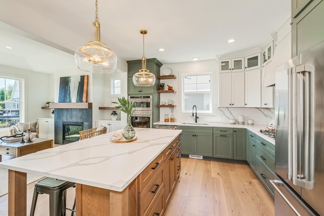 kitchen featuring a healthy amount of sunlight, a tiled fireplace, appliances with stainless steel finishes, and a sink