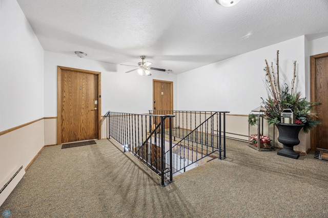 hallway with carpet floors, a baseboard radiator, and a textured ceiling