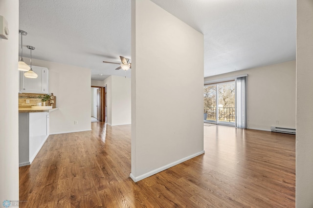 unfurnished living room featuring ceiling fan, light hardwood / wood-style flooring, a baseboard radiator, and a textured ceiling