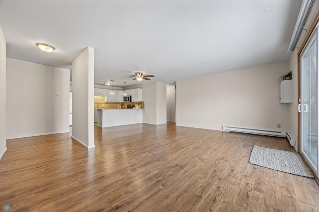 unfurnished living room featuring light wood-type flooring, ceiling fan, and a baseboard heating unit