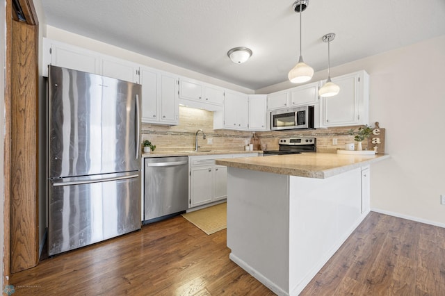 kitchen with backsplash, hanging light fixtures, appliances with stainless steel finishes, white cabinetry, and kitchen peninsula