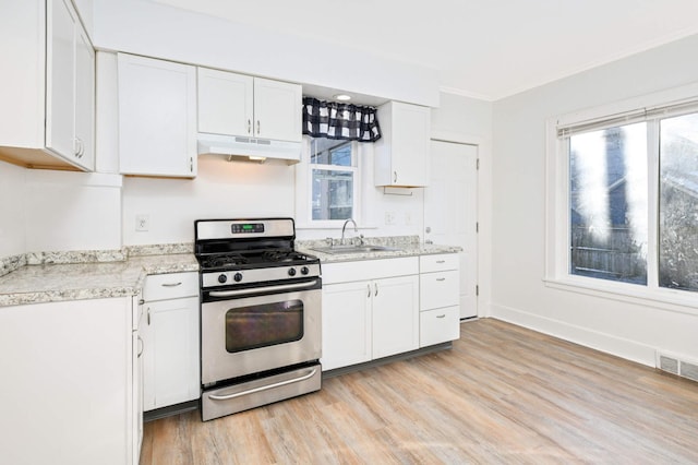 kitchen featuring white cabinets, crown molding, sink, light hardwood / wood-style floors, and gas stove