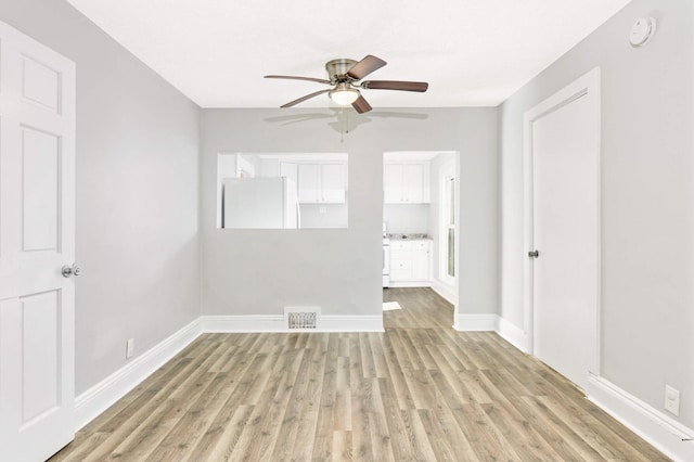 empty room with ceiling fan and light hardwood / wood-style flooring