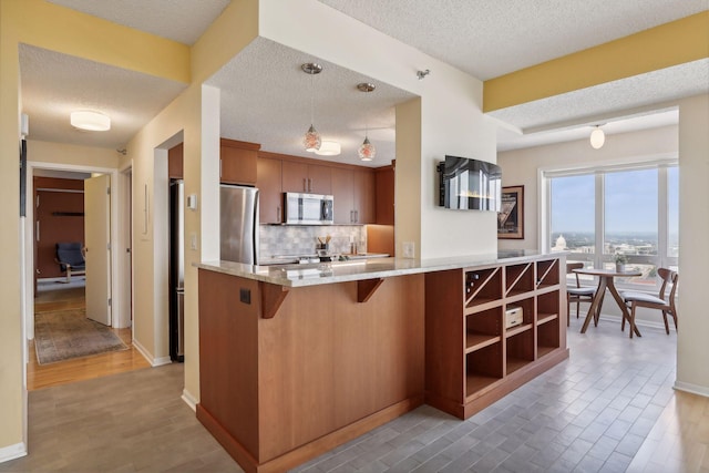 kitchen with kitchen peninsula, pendant lighting, a textured ceiling, and appliances with stainless steel finishes