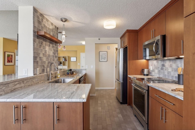 kitchen with sink, appliances with stainless steel finishes, tasteful backsplash, light stone counters, and kitchen peninsula