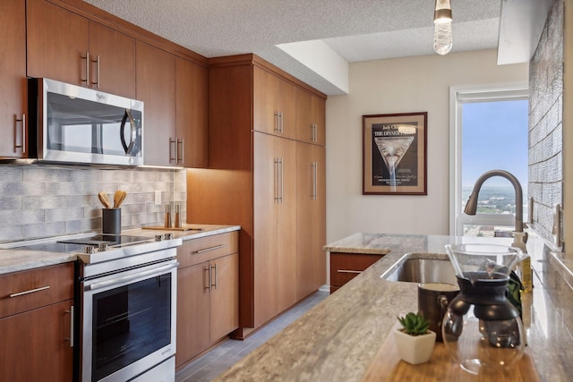 kitchen with a textured ceiling, stainless steel appliances, tasteful backsplash, and sink