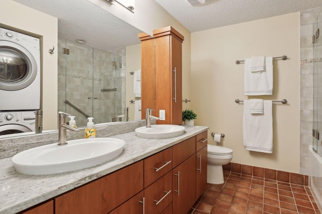 bathroom featuring vanity, toilet, stacked washing maching and dryer, and a textured ceiling