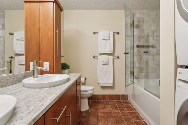 full bathroom with enclosed tub / shower combo, toilet, stacked washing maching and dryer, and vanity