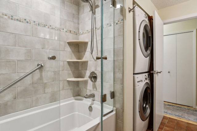 bathroom with a textured ceiling, tiled shower / bath, and stacked washer / drying machine