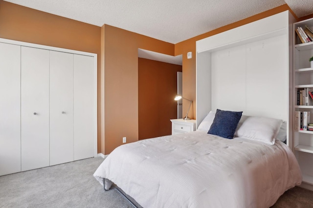 carpeted bedroom with a textured ceiling and a closet