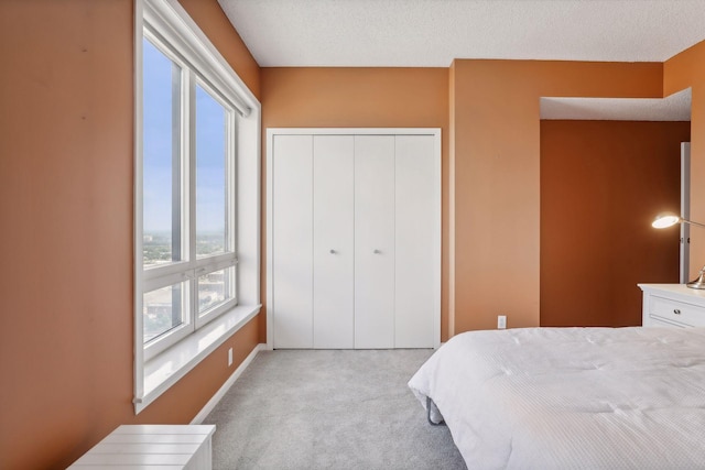 bedroom featuring light carpet, a textured ceiling, and a closet