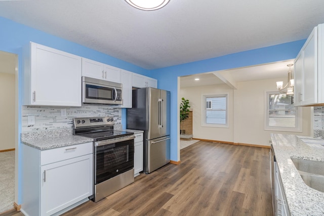 kitchen featuring decorative backsplash, stainless steel appliances, white cabinetry, and light stone countertops