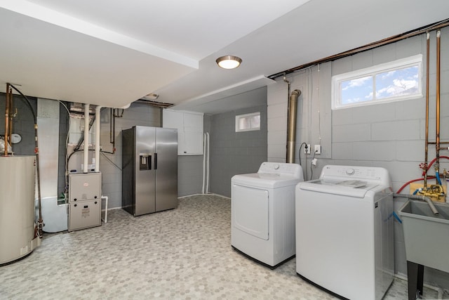 clothes washing area featuring heating unit, gas water heater, sink, and washing machine and clothes dryer