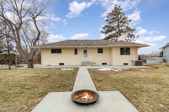 rear view of house with a lawn, central air condition unit, and an outdoor fire pit