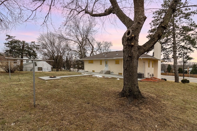 yard at dusk featuring central air condition unit