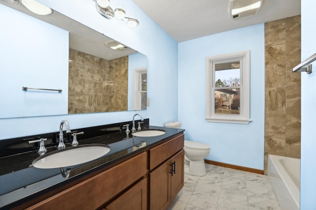 full bathroom with vanity, a textured ceiling, toilet, and tiled shower / bath